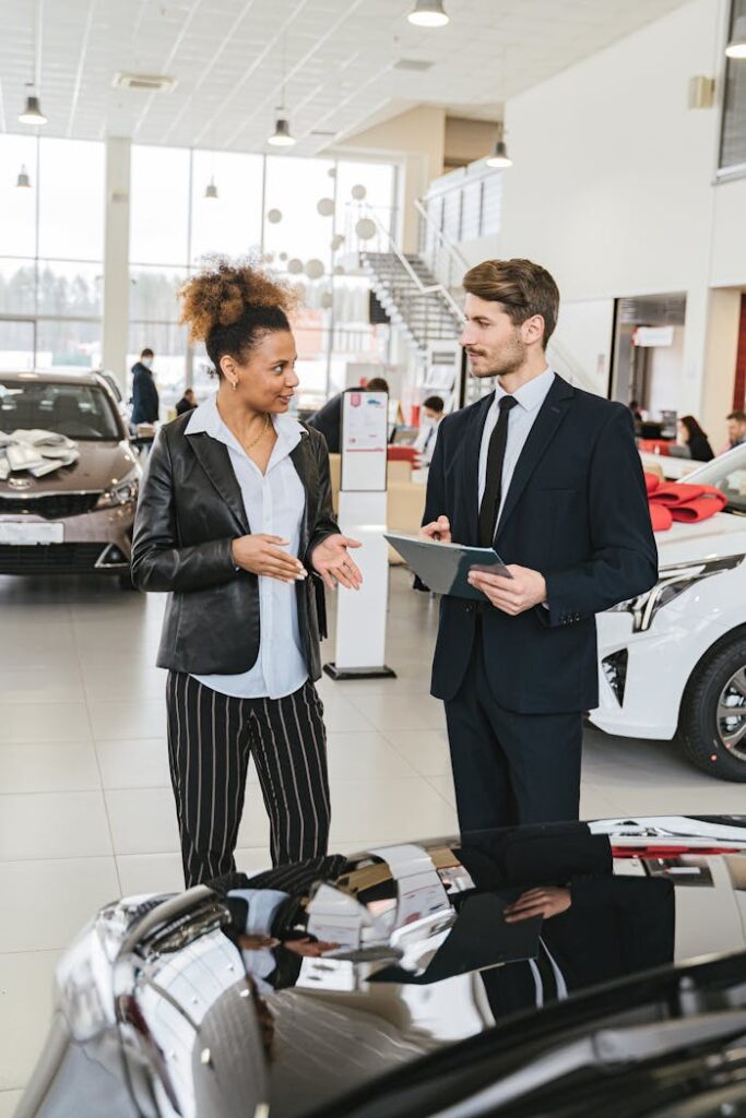 Business professionals discussing details in a car dealership showroom.